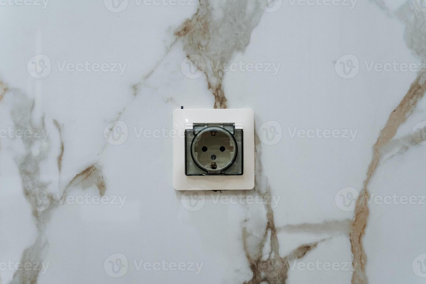 There is a white electrical outlet installed on a beautiful marble wall, accentuating the elegant design of the space. This outlet is compatible with various AC power plugs and sockets photo