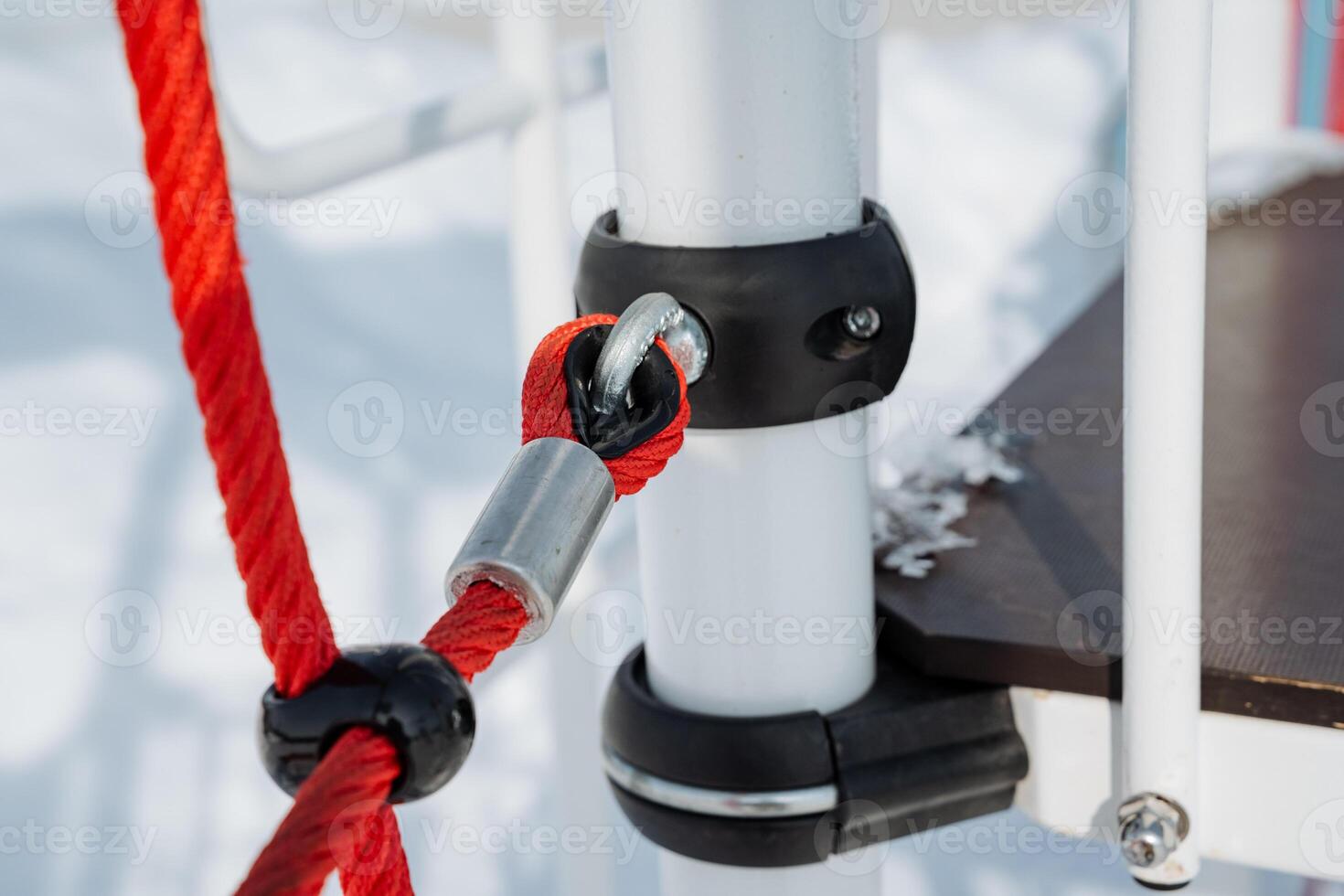 Closeup view of the playground equipment connection, featuring a rope and metal clamp attachment set against a picturesque winter scenery, highlighting its intricacies photo
