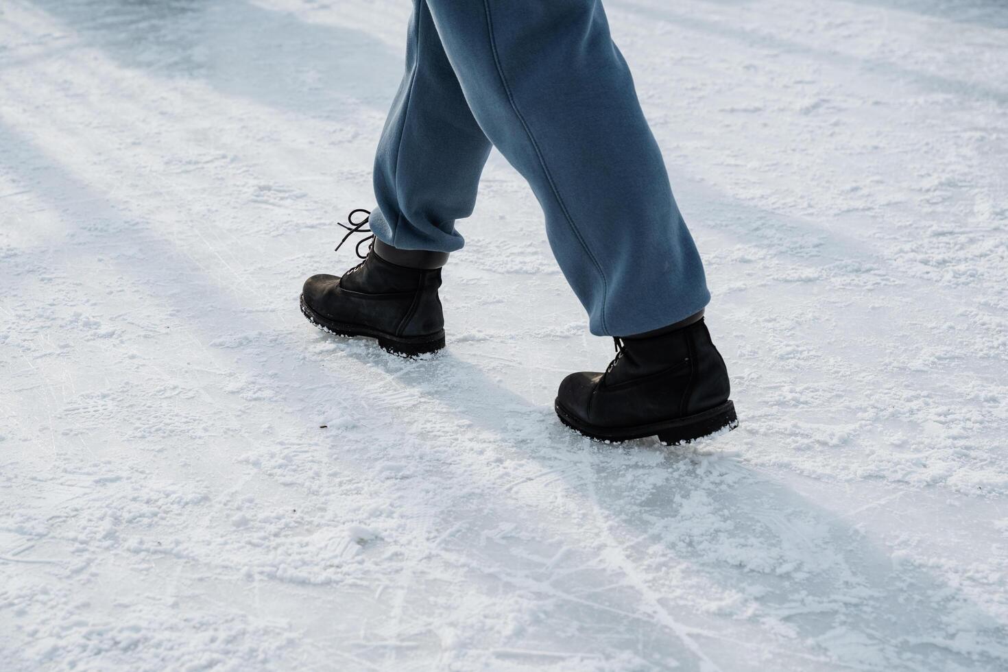 A person walking gracefully on snowy ground while wearing winter boots, embodying a vibrant winter lifestyle scene filled with adventure and enjoyment amid the frosty landscape photo