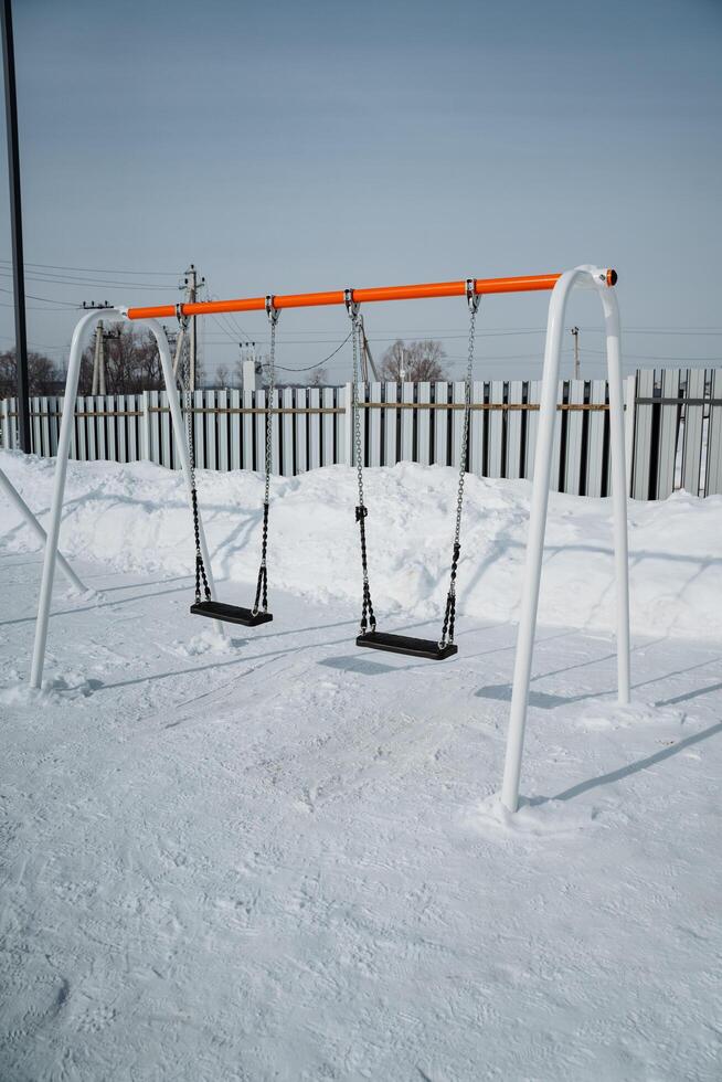 An Isolated Swing Set Nestled Within a Beautiful Winter Wonderland A Stunning and Peaceful Playground Scene, Covered Generously in a Soft Layer of Sparkling Snow and Stillness photo