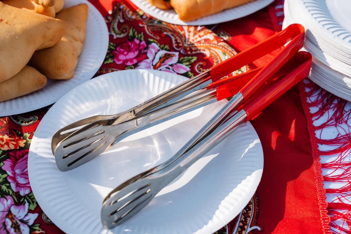 A vibrant and colorful set of serving tongs and plates beautifully arranged and set up for an enjoyable picnic or outdoor gathering, perfect for entertaining guests photo