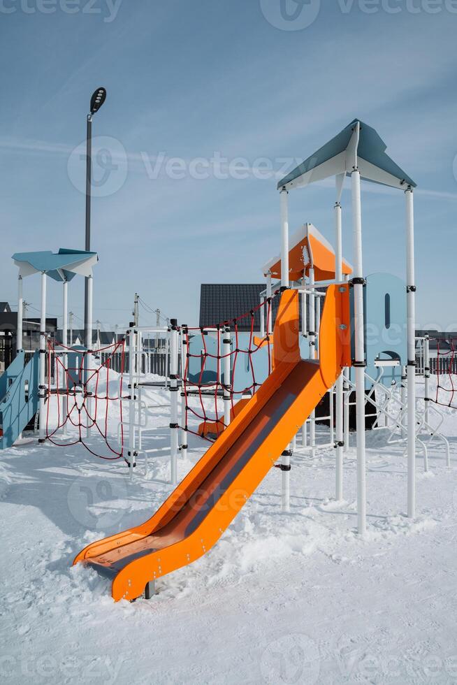 A vibrant and colorful playground slide, beautifully surrounded by a blanket of snow, creates an enchanting winter landscape for children to enjoy and explore safely photo