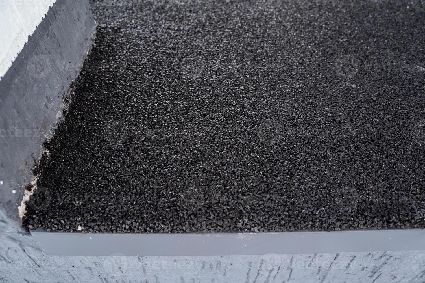 This image provides a closeup view of a black bituminous roof surface, showcasing its textured finish and appearance, ideal for construction and rooftop applications photo