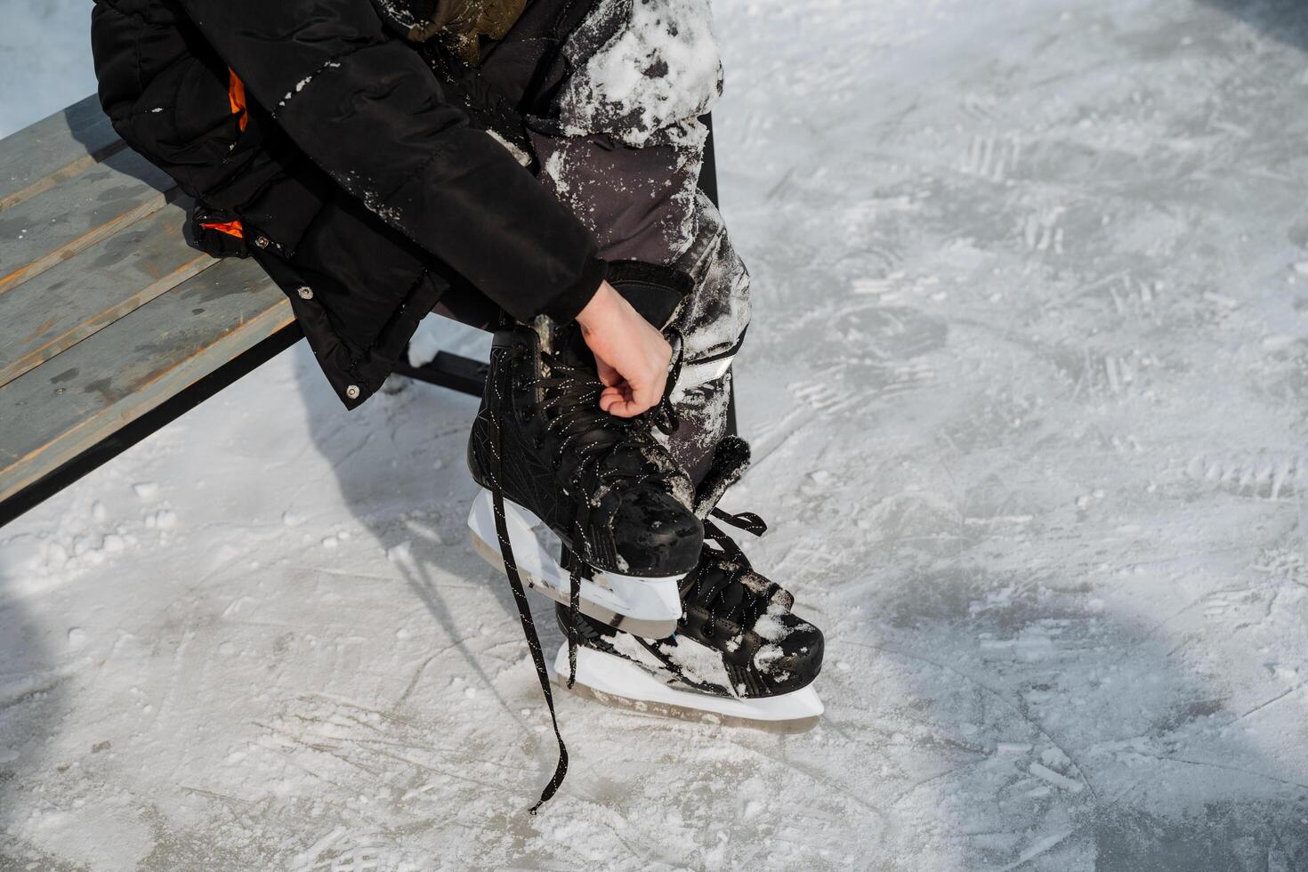 Getting Ready for Ice Skating A Dedicated Skater Skillfully Tying Their Laces Right on the Ice Rink as They Eagerly Prepare for an Exciting Time Full of Fun and Fitness photo