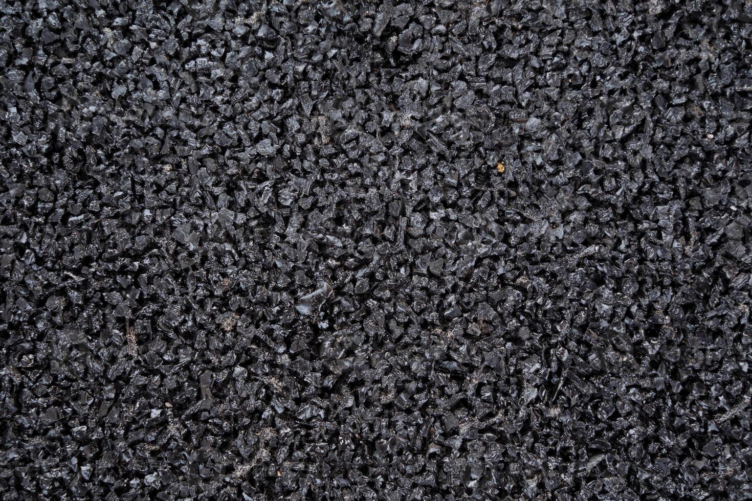 This is a closeup view of black rubber granules, which are ideal for use in sports flooring and playground surfaces. They ensure both safety and durability for users photo
