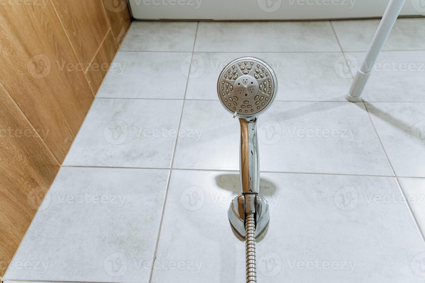 In a spacious bathroom, a modern shower head is elegantly positioned above a stylishly tiled floor, enhancing both the visual attractiveness and the practical functionality of the area photo