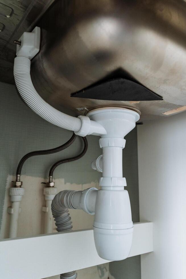 A kitchen sink that features a drain pipe situated beneath it, an essential element of kitchen plumbing that facilitates the removal of waste water effectively and efficiently photo