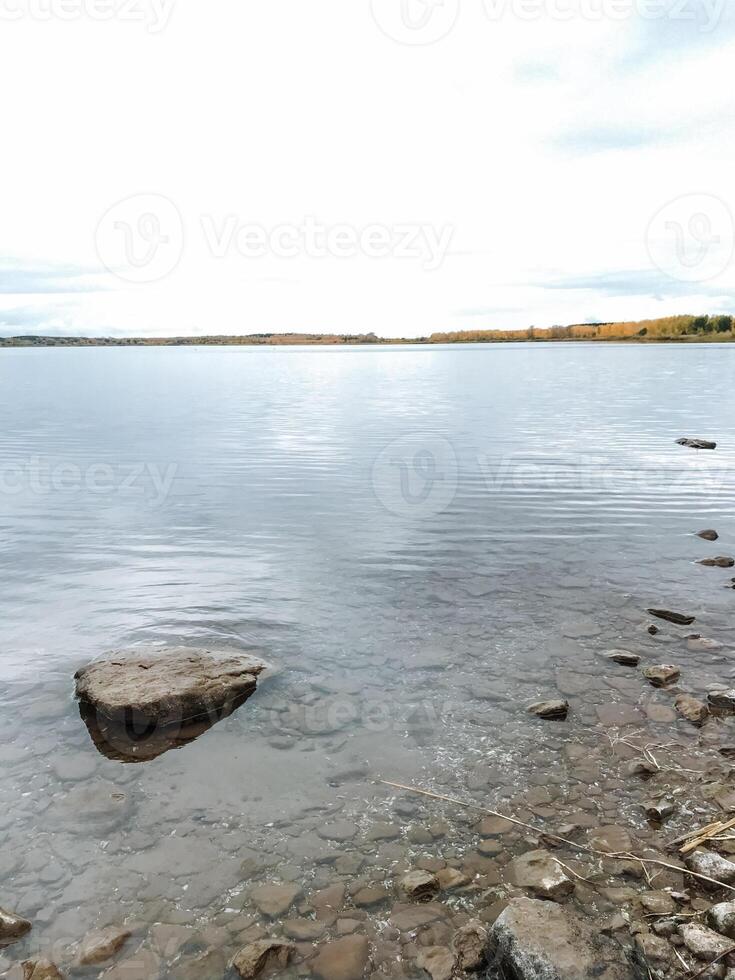 A large body of water with a rock in the middle of it photo