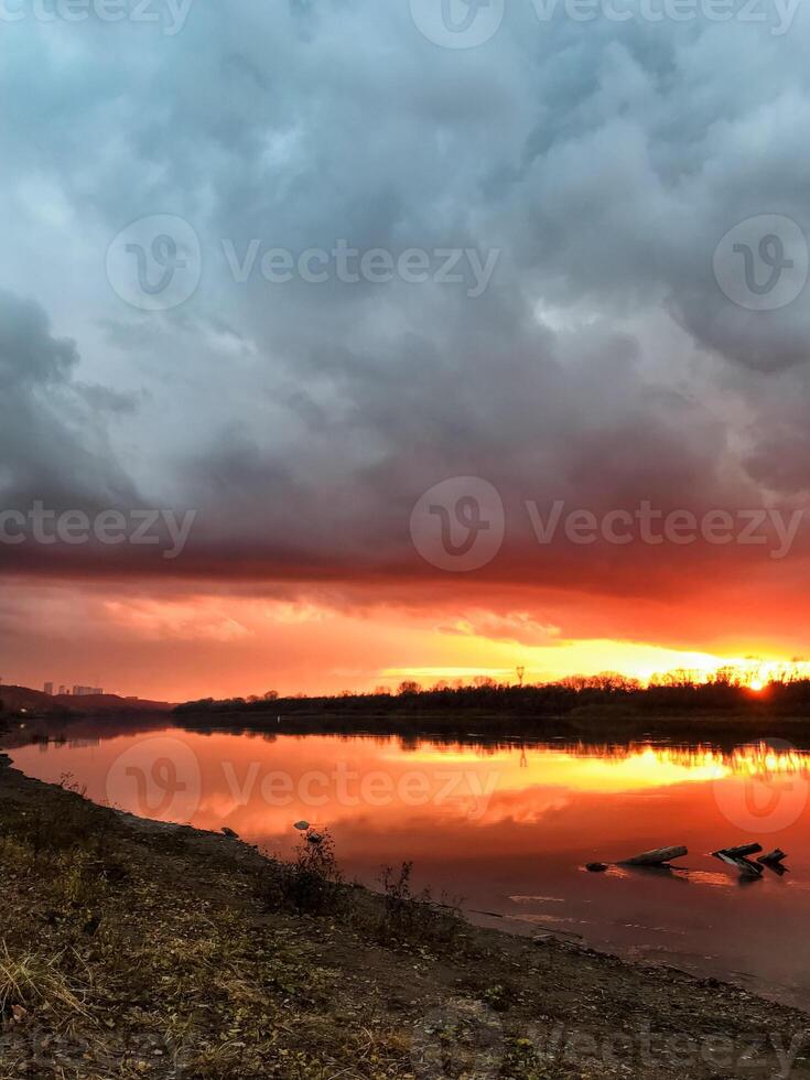 The breathtaking view of a colorful sunset casting its vibrant hues over a serene lake, complemented by a beautifully textured cloudy sky, creates a perfect natural scene of tranquility photo