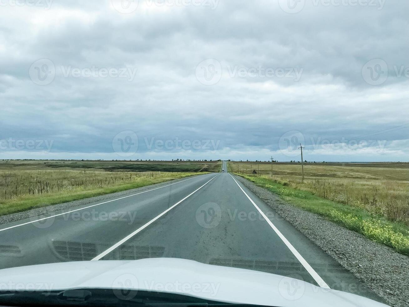 A car is smoothly driving along a picturesque countryside road on a moderately cloudy day, relishing the beautiful views of nature while skillfully navigating the wellpaved path ahead photo