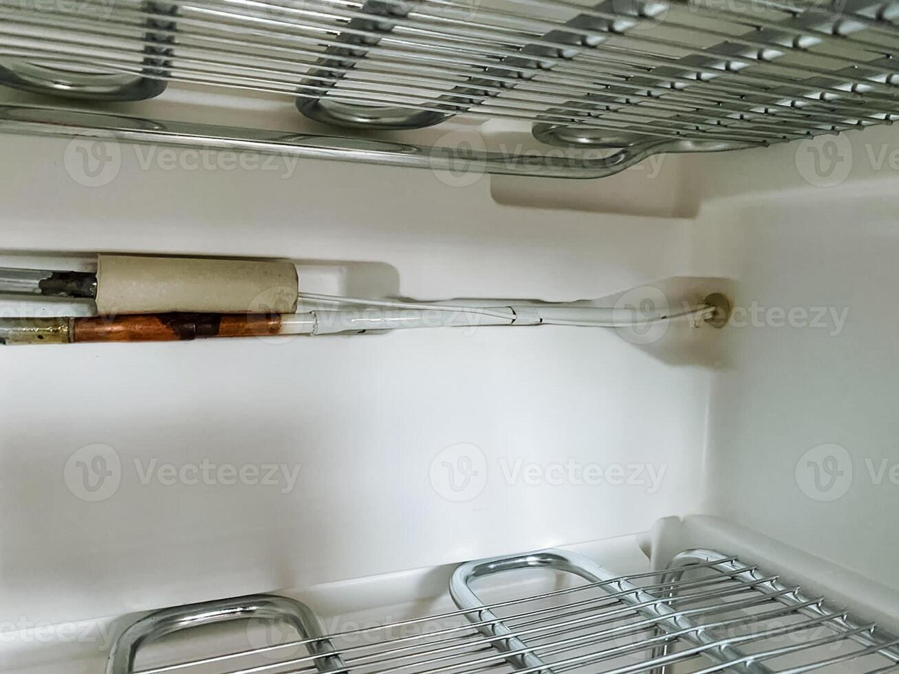 Inside an empty refrigerator, there is a wire shelf that is currently unoccupied, providing space for various food items and beverages. This appliance is an essential in any kitchen photo