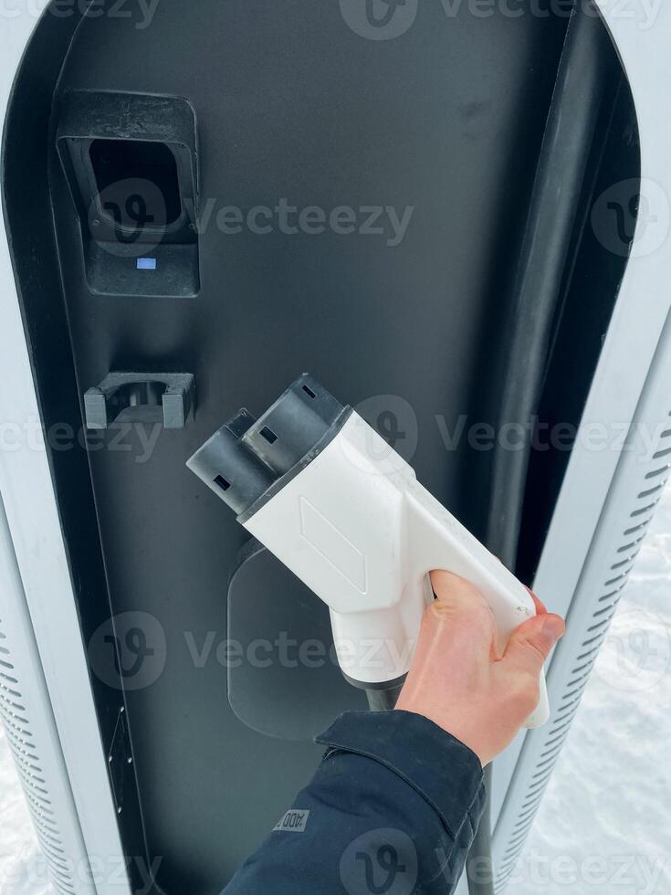 A person is connecting their electric vehicle to a charging station, ensuring that it is powered up and ready for use, showcasing the advancements in technology and electric mobility photo