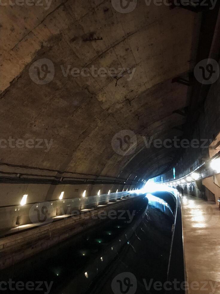 A dark and mysterious tunnel, which is dimly illuminated by a few flickering lights mounted on the walls, creates an eerie atmosphere that greatly enhances the overall sense of adventure photo