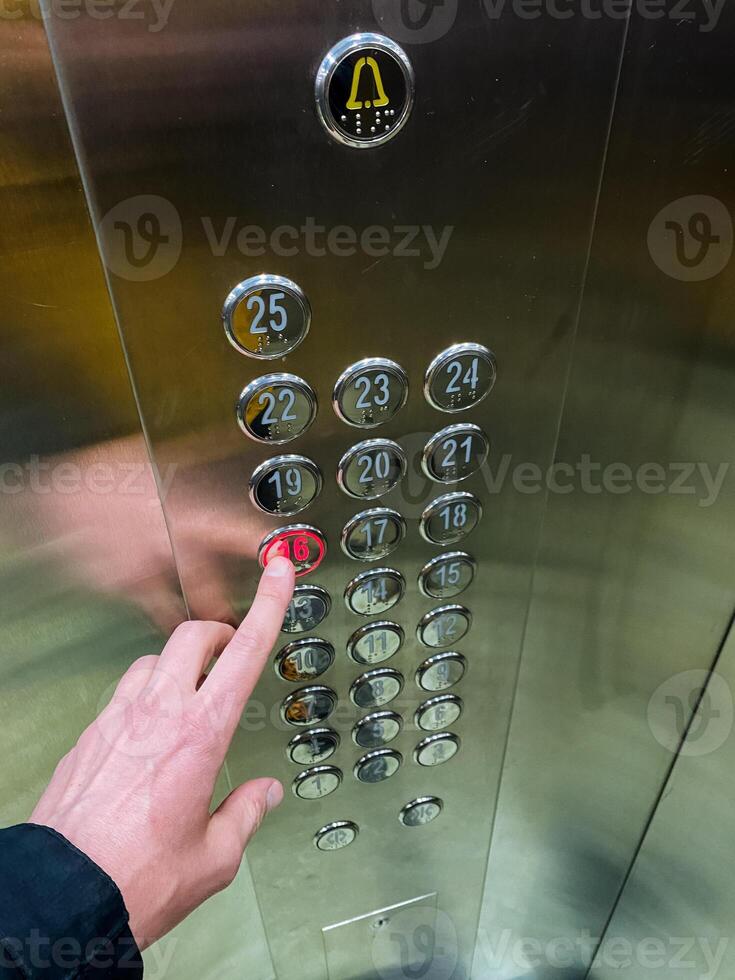 A person is vigorously pressing a bright red button inside the elevator, which is essential for selecting different floors and operating it efficiently for smooth transportation photo