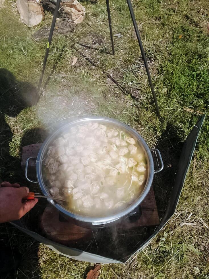 A person is actively stirring a pot of delicious soup using a wooden spoon, enhancing the flavors as it simmers. This process is essential for creating an enjoyable meal photo