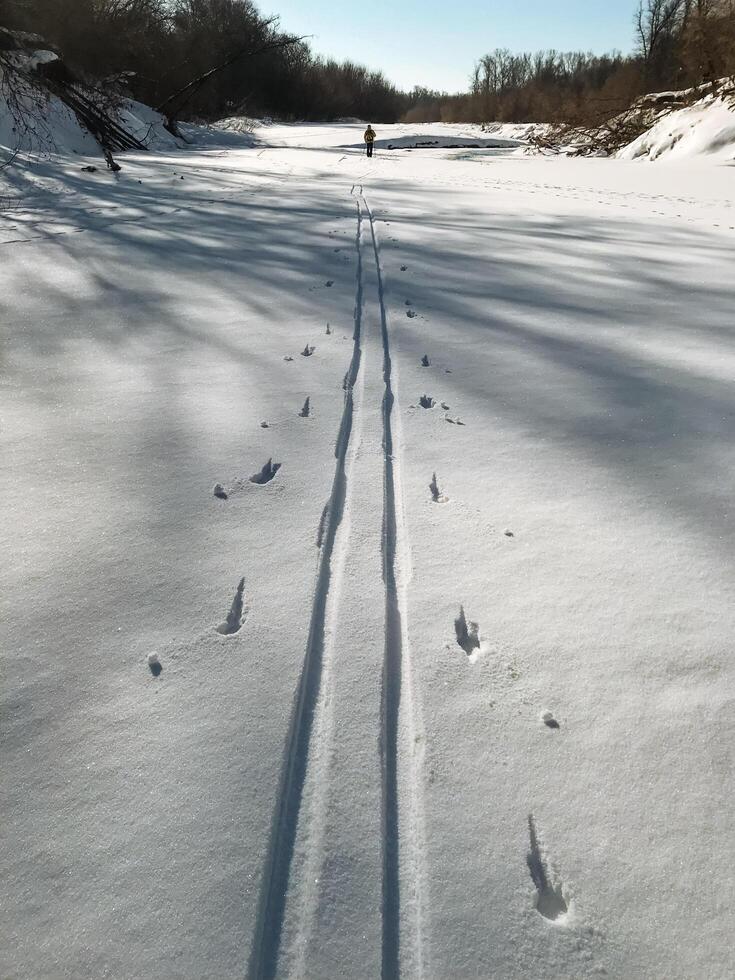 A person elegantly skis down a beautiful snowcovered road, surrounded by a stunning winter landscape that showcases the charm of freezing temperatures and glistening ice photo