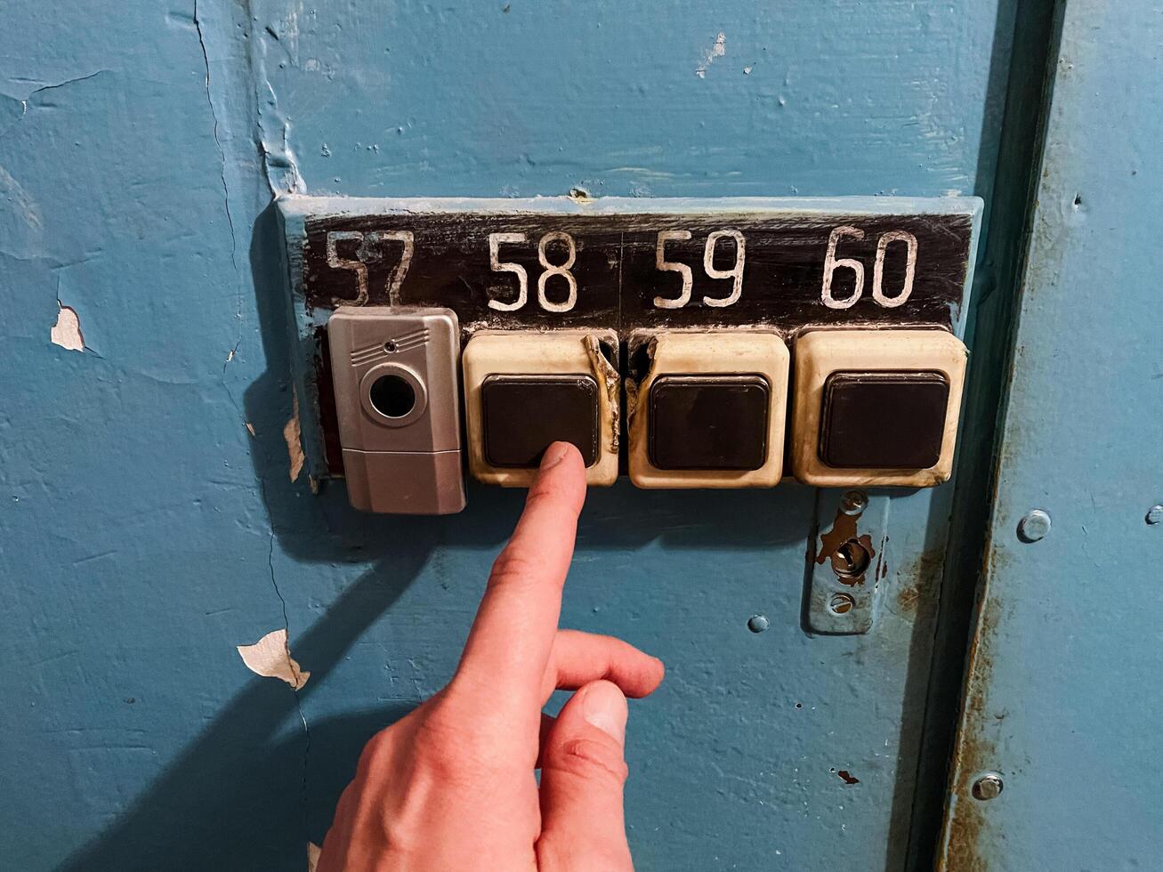 A persons finger is currently pointing directly at the specific number 57 that is displayed on a vibrant blue door, indicating an important or significant reference point photo