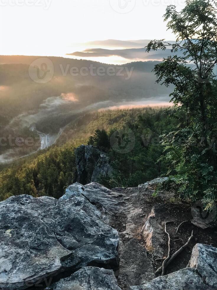 The breathtaking view of a vast mountain valley can be admired from the top of a rugged rocky cliff, showcasing the beauty of natures majesty and serene wilderness all around it photo