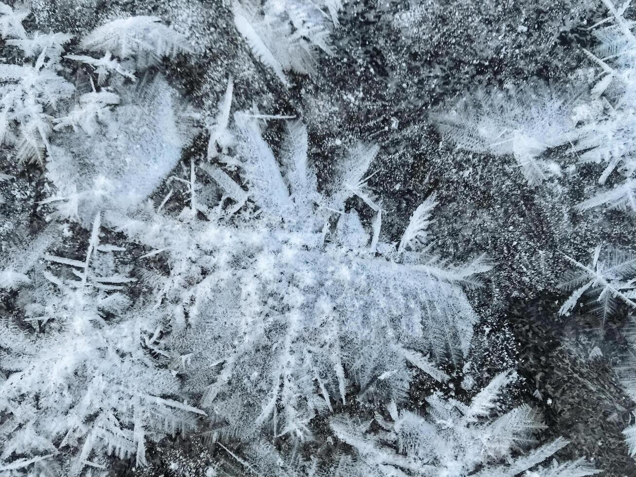 This closeup image shows captivating ice crystals on a rugged rock, showcasing winters beauty and natures artistry through mesmerizing frost patterns in cold conditions photo