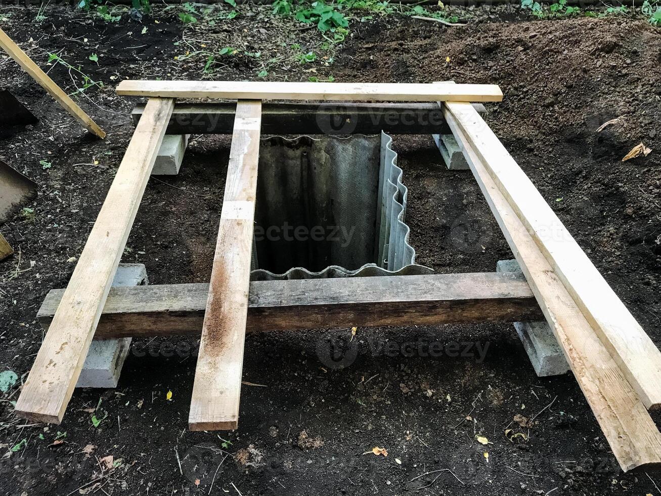 A deep hole that exists beneath the Earths surface is currently being reinforced with a robust wooden frame to provide essential support and stability during both its use and access photo