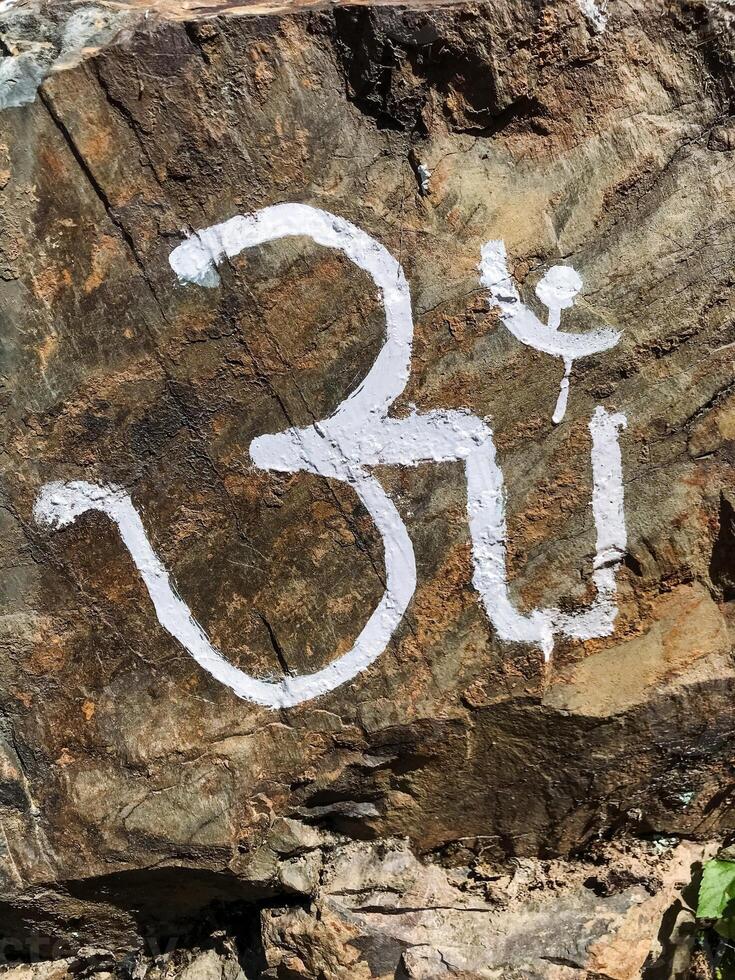 The word om is vibrantly painted on a large rock, symbolizing peace and spirituality, contrasting with the earthy brown rust of the bedrock beneath, enhancing its beauty photo