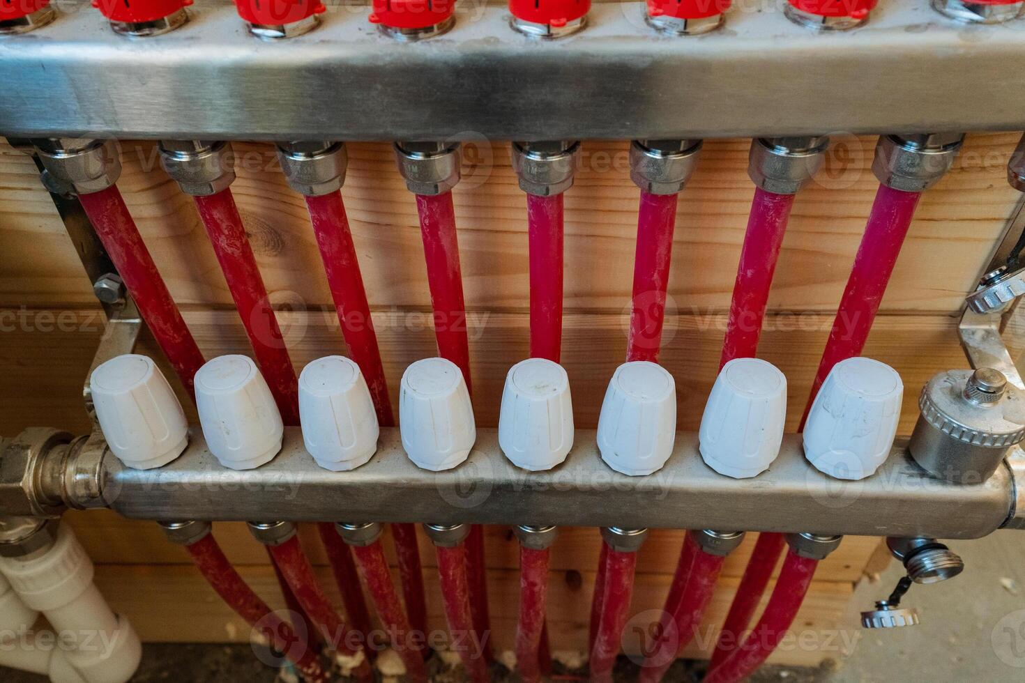 The robust and durable bright red pipes are meticulously connected to a heating unit, which together create an efficient plumbing network that ensures warmth and comfort in any living space photo