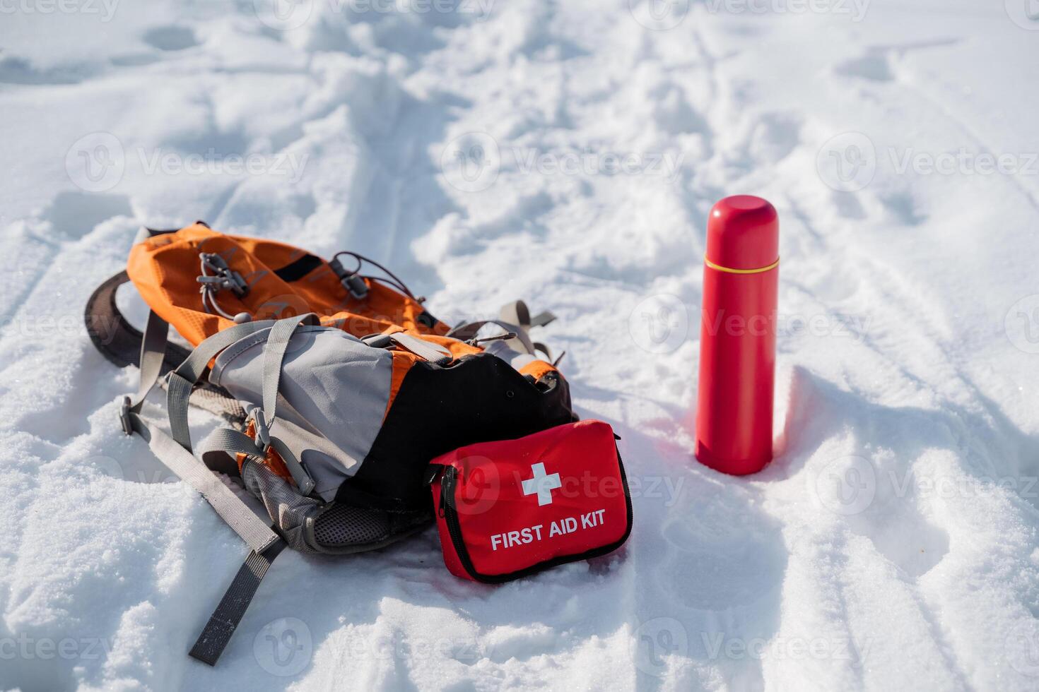 A backpack and a first aid kit can be seen resting on the snow, indicating someones preparedness for winter adventures or emergencies in the great outdoors. Careful planning is essential photo
