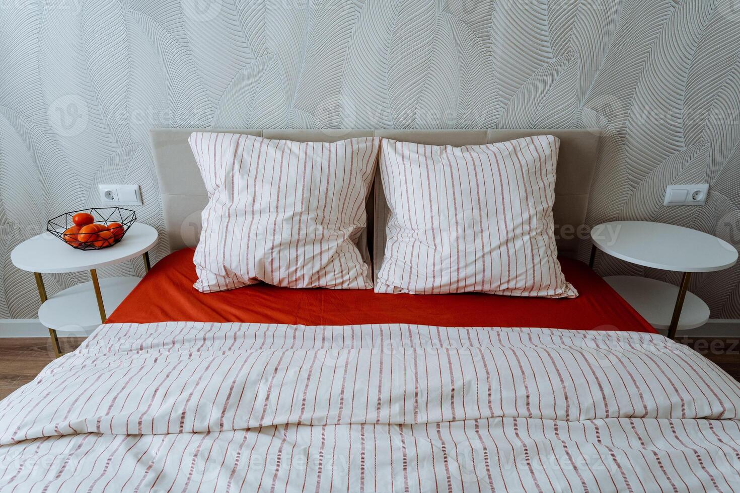 In a cozy bedroom, there is a comfortable bed adorned with vibrant red sheets and soft white pillows that provide a beautiful contrast and enhance the overall aesthetic of the room photo