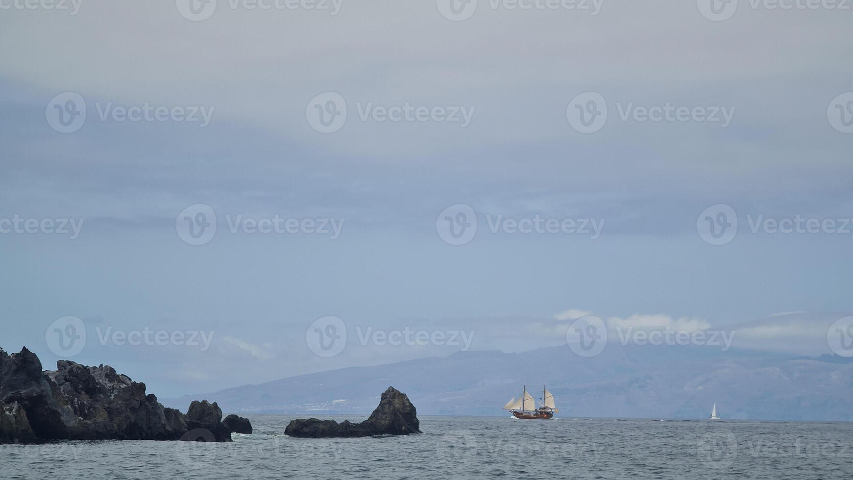 Black rocks and ship in the ocean photo