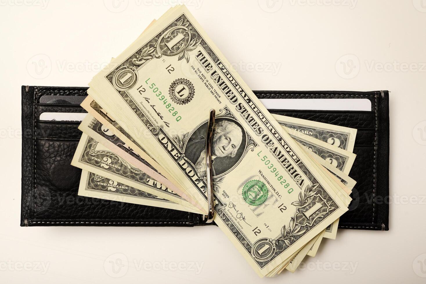A dark-toned cash holder showcasing greenbacks on a white base. photo