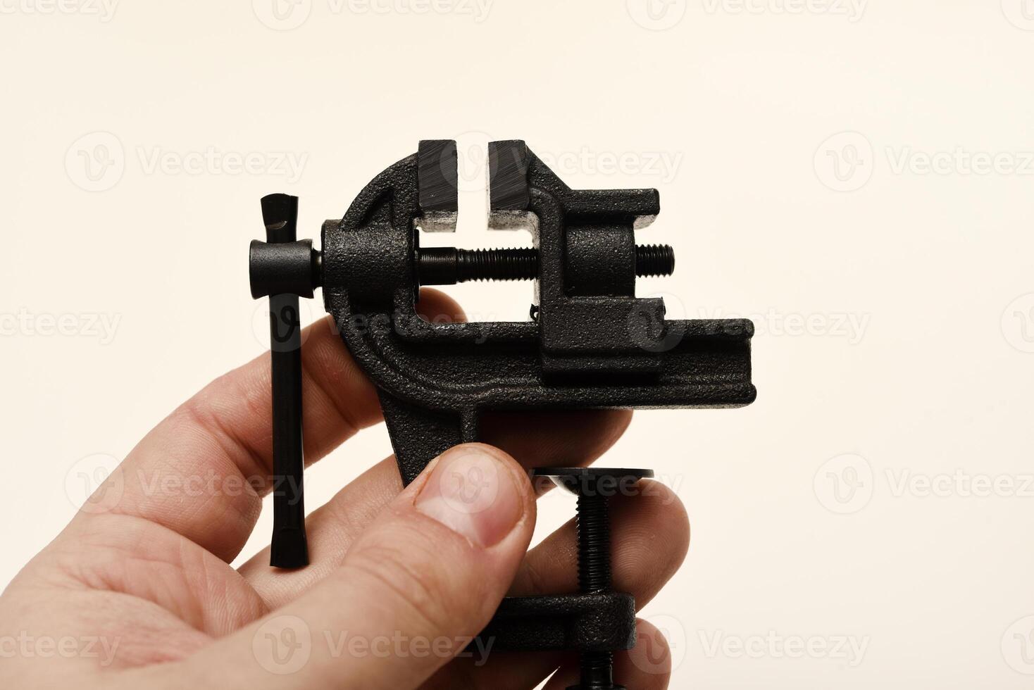 A tiny metal clamp in his hand. The gripping tool. Locksmith equipment. photo