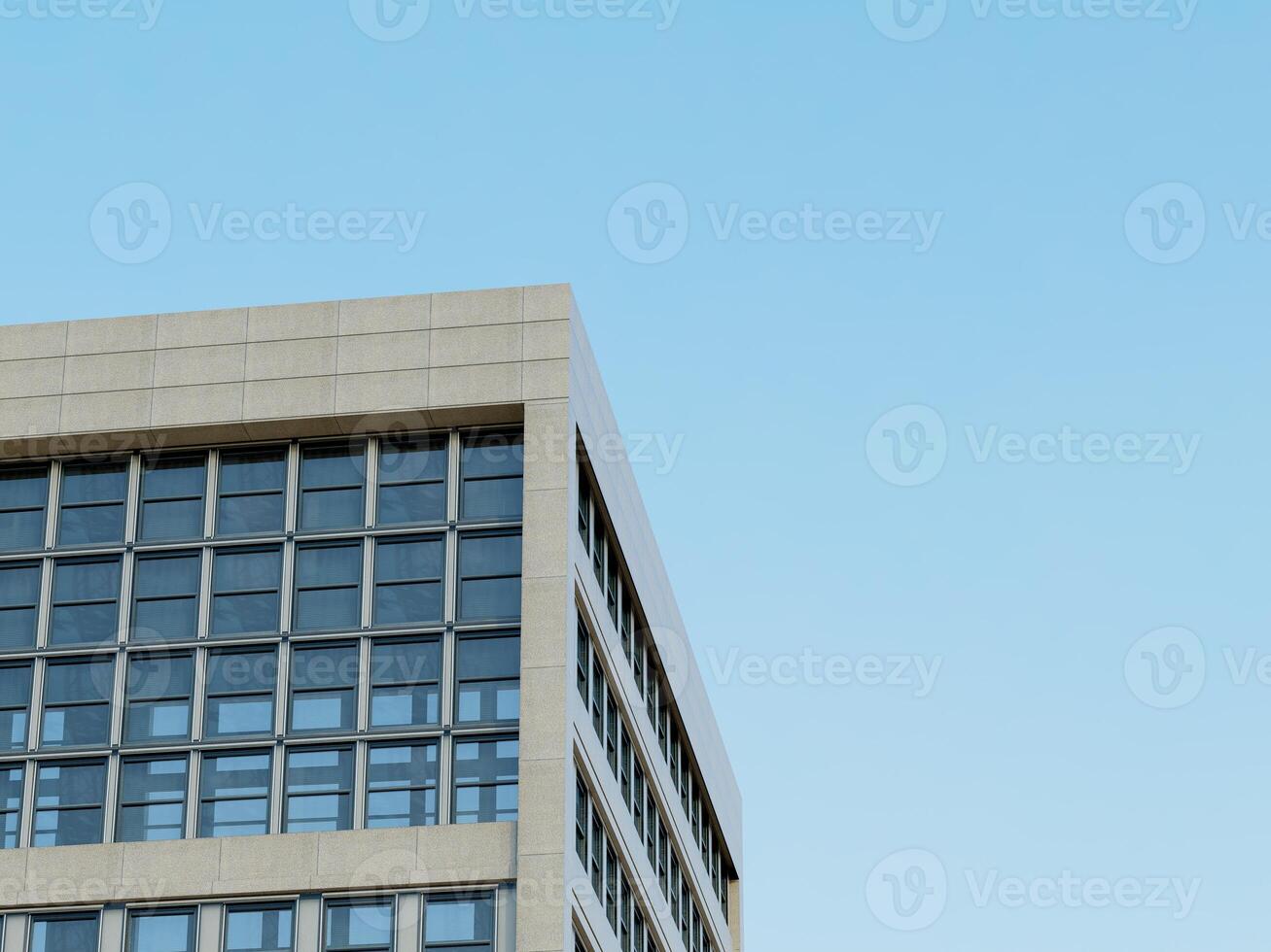 Corner of a contemporary building with a polished stone surface and blue sky. photo