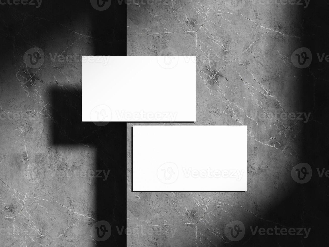 A modern and professional business card mockup with soft shadows cast over a textured dark stone background, ideal for branding projects. photo