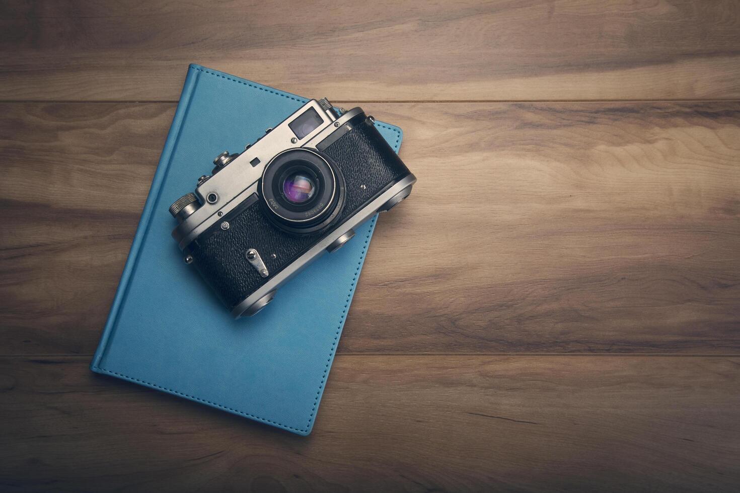 A vintage camera and a notebook on a wooden table photo