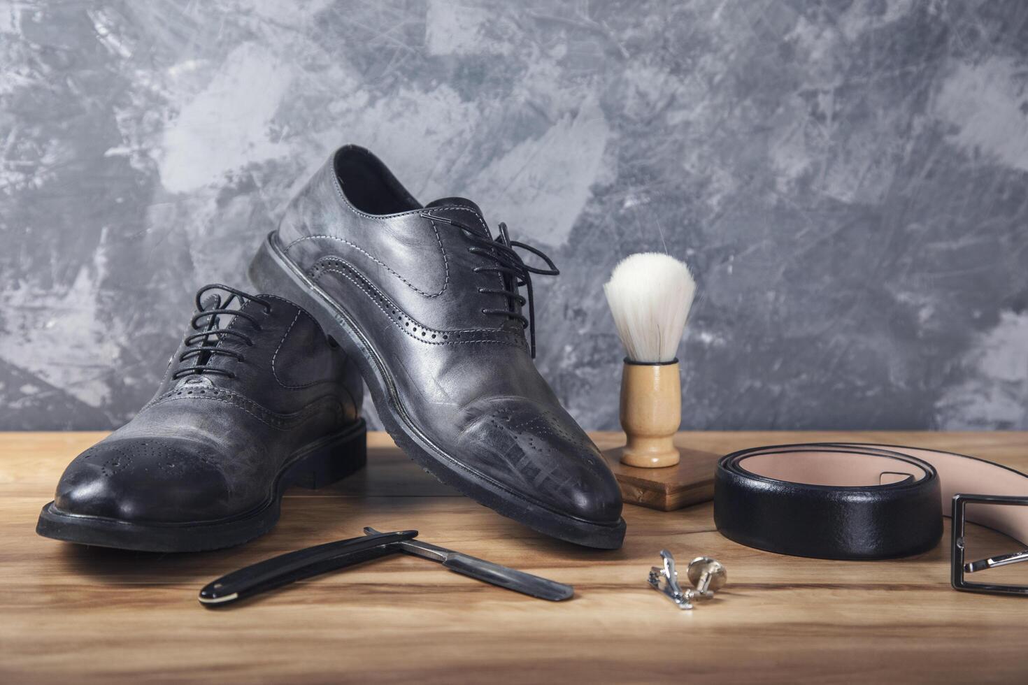 Mens shoes, a razor, and a comb on a wooden table photo