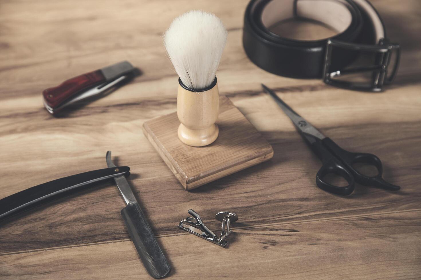 A wooden table with a shaving brush, scissors, belt and other tools photo