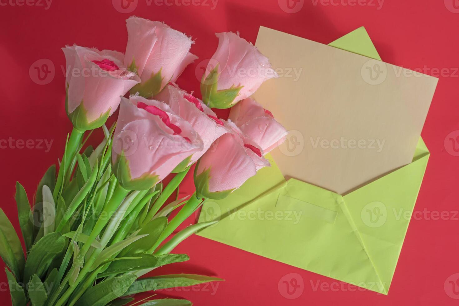 Pink tulips and envelope on red background photo
