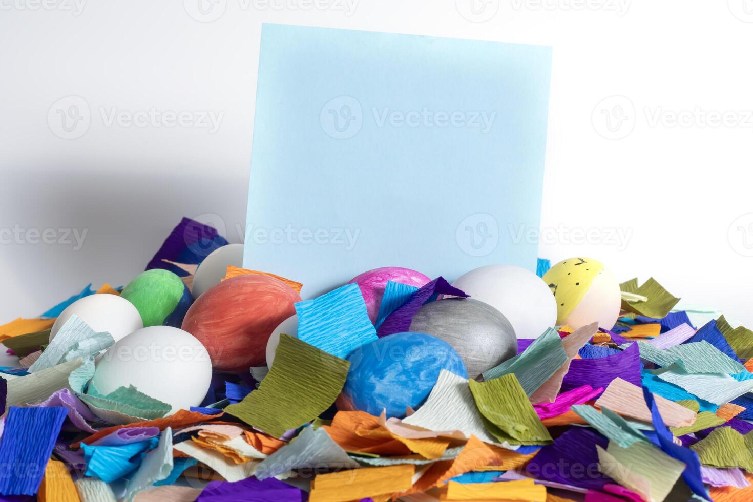 A pile of colorful confetti and an easter egg with a blank card photo