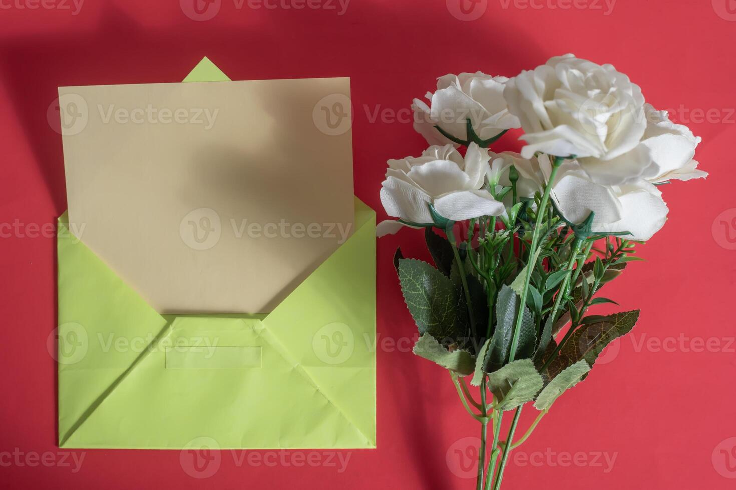 An open green envelope with white roses on a red background photo