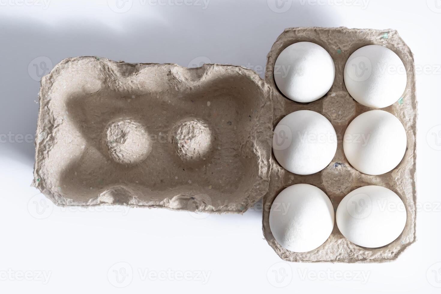 Cardboard box with six white eggs on a bright white background photo