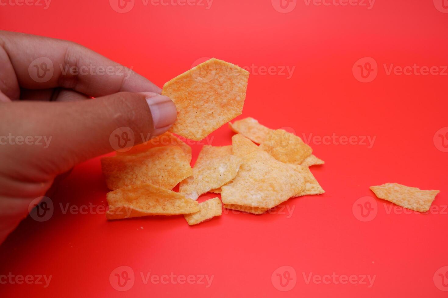 Hexagon-Shaped Potato Snack in Hand Against Red Backdrop photo