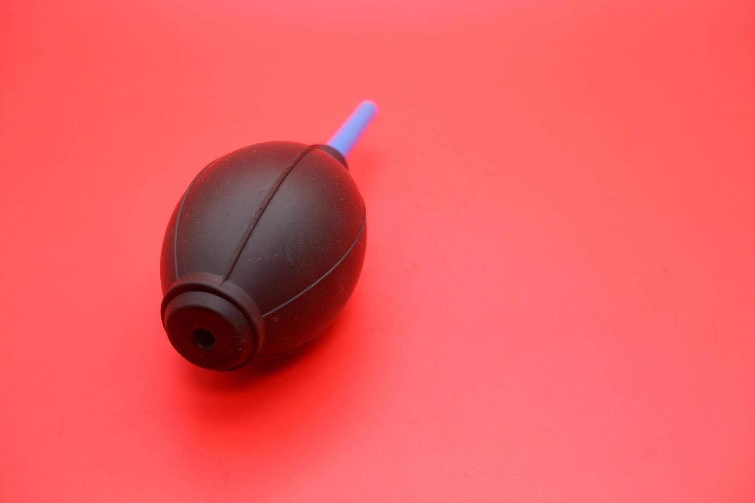 Rubber air blower isolated on a vibrant red background, showcasing its design and details. photo