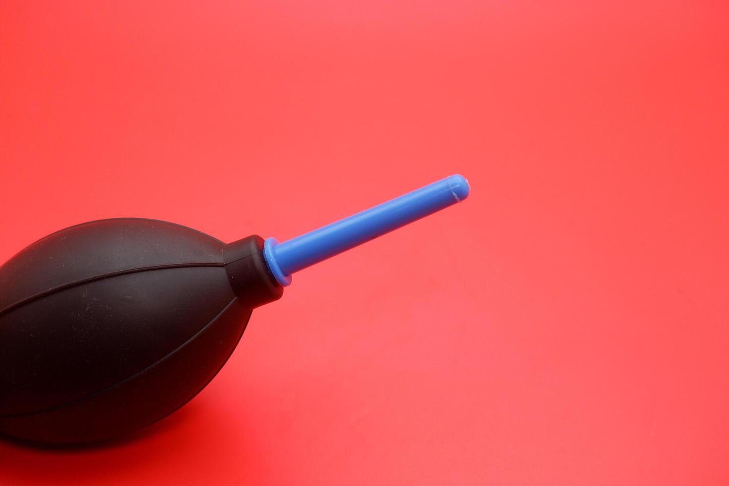 Single rubber air blower set against a red background, with clear details and sharp contrast. photo