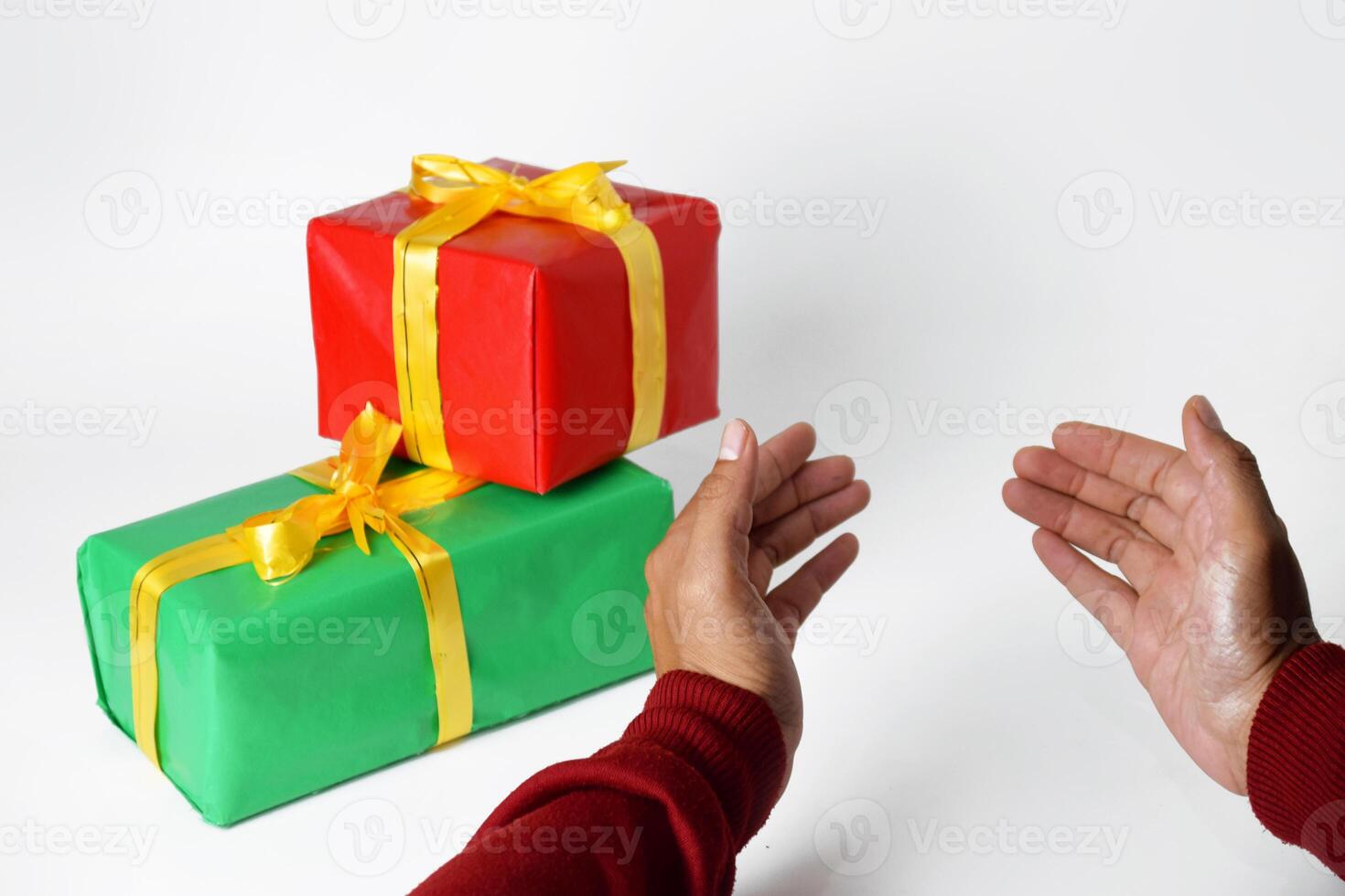Hand of a person in a red sweater shows a red and green gift box photo