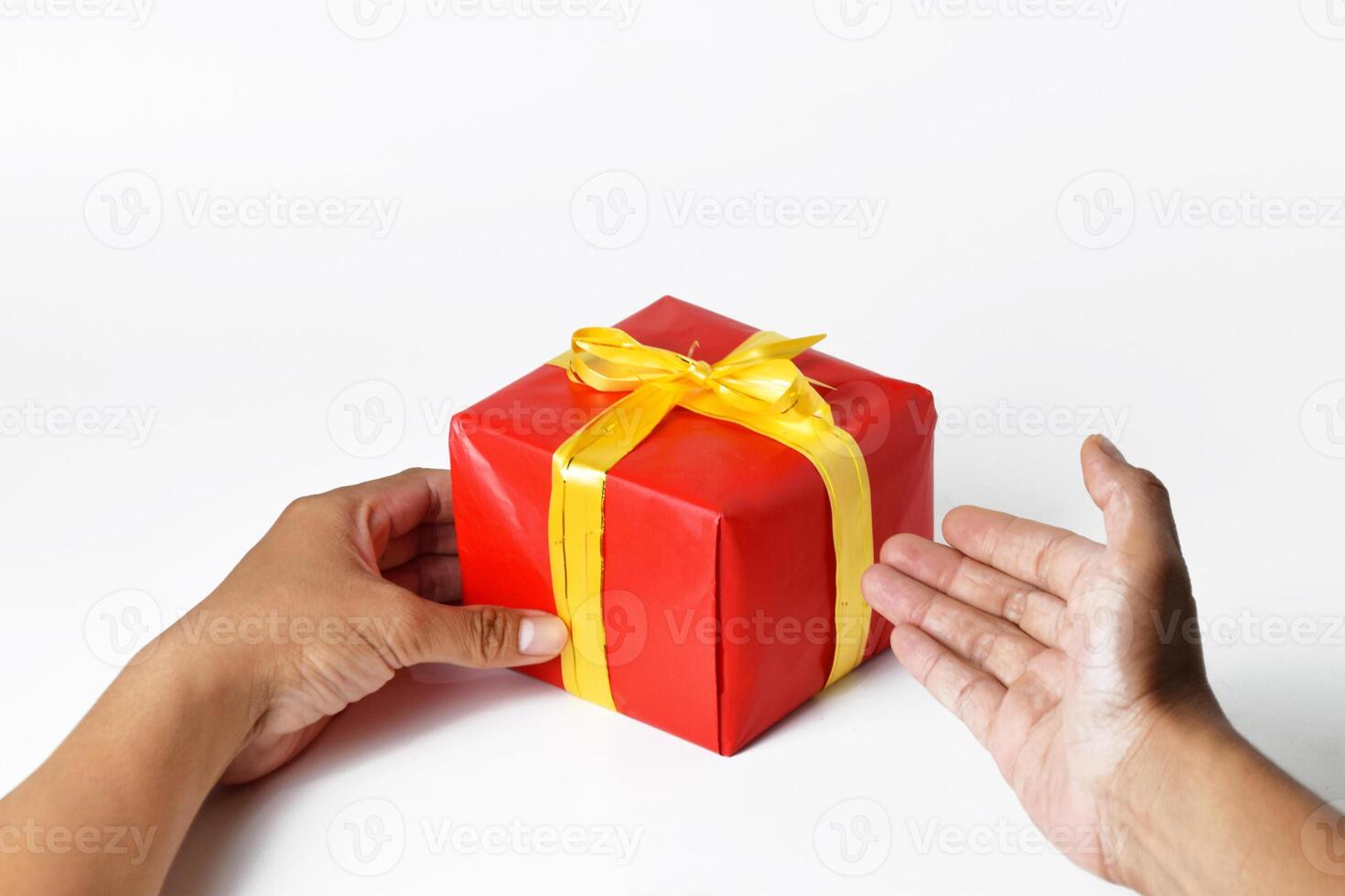 A Hand Presenting a Red Gift Box with a Golden Ribbon photo