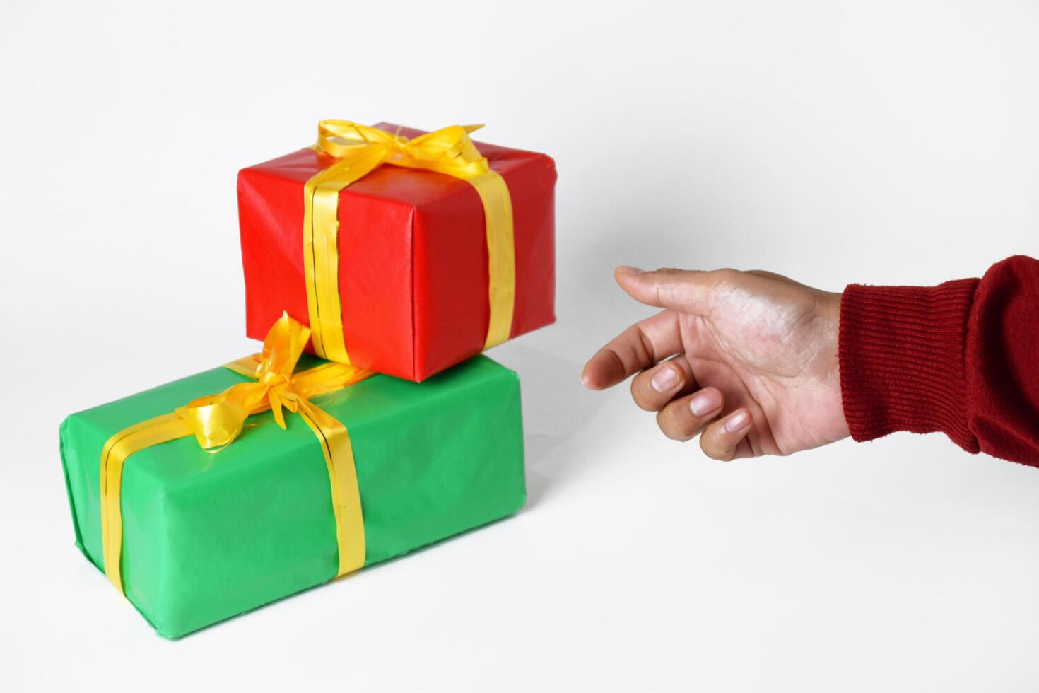 A hand of a person in a red sweater shows a red and green gift box photo
