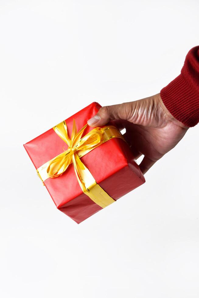 A hand in a red sweater touching a red gift with a yellow ribbon photo