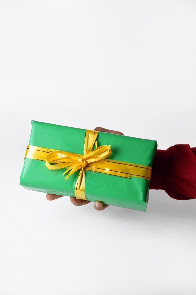 A Festive Touch Red-Sleeved Hand Holding a Green Present photo