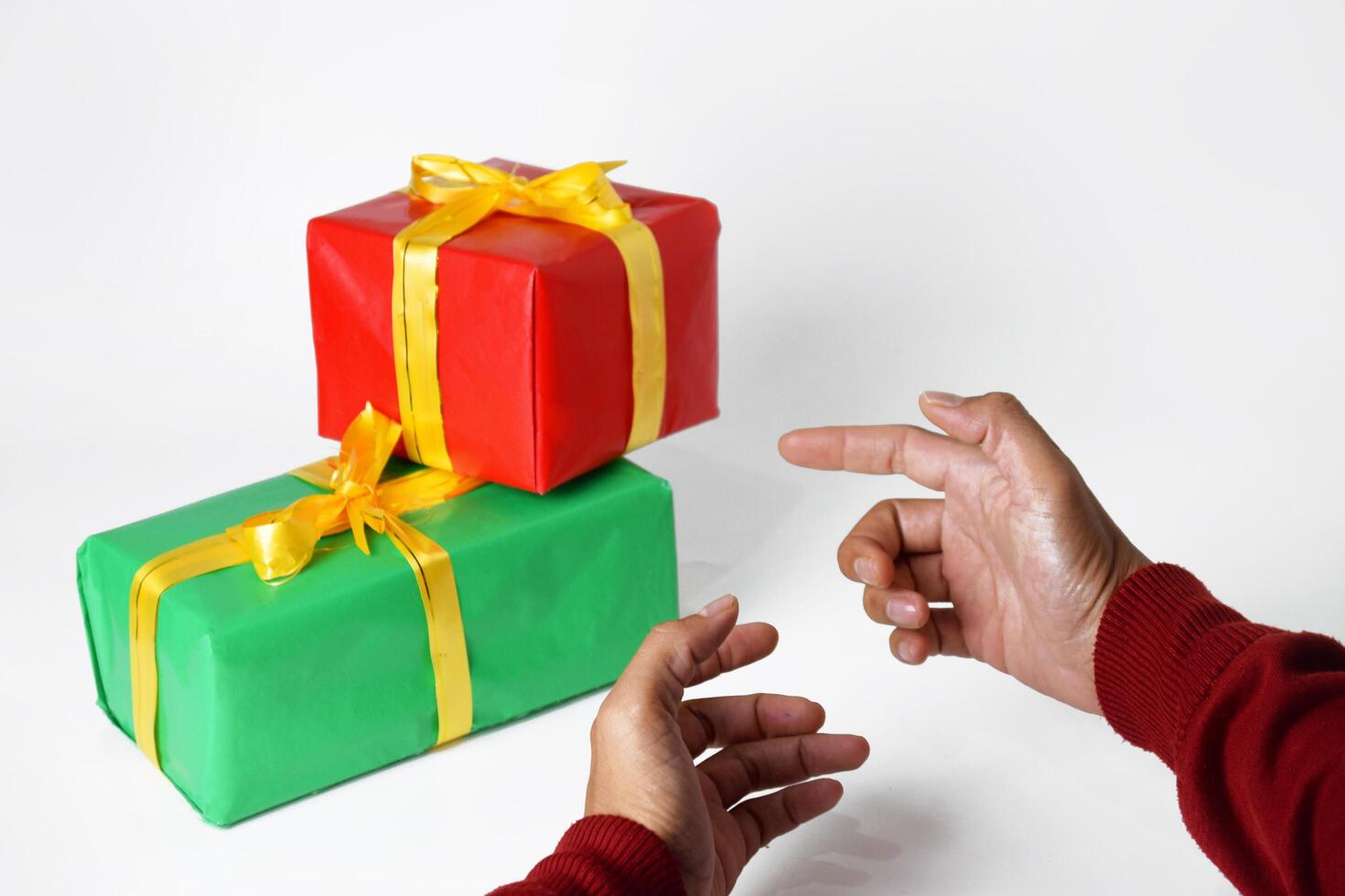 The hand of a person in a red sweater shows a red and green gift box photo