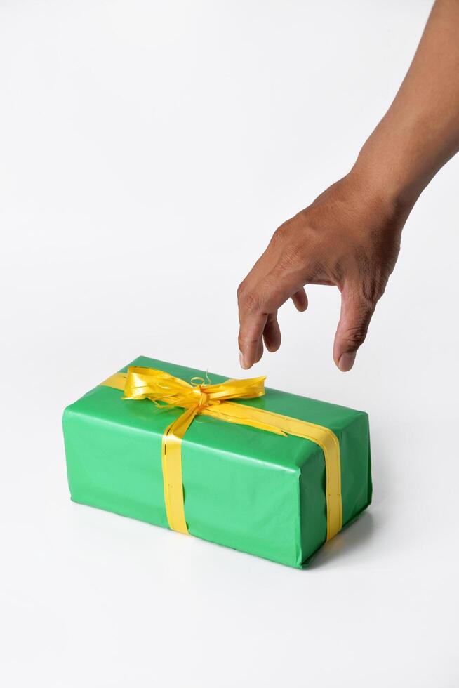 A hand presenting a green gift box against a white background photo